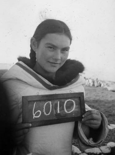 Young woman holding number, Pond Inlet, Nunavut, 1945. Photo: Arthur H. Tweedle / Library and Archives Canada / e002344280
