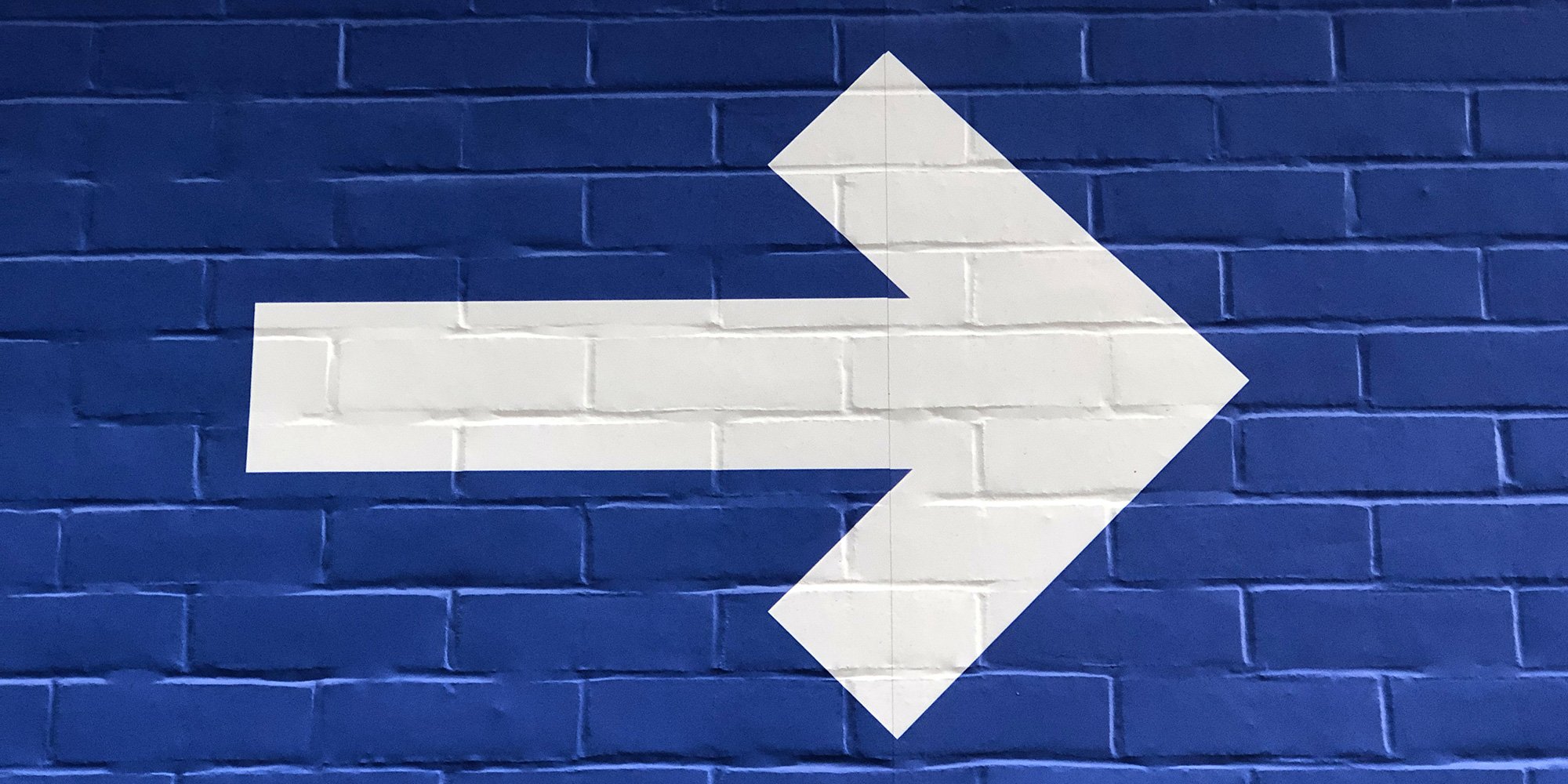 white arrow on blue brick wall