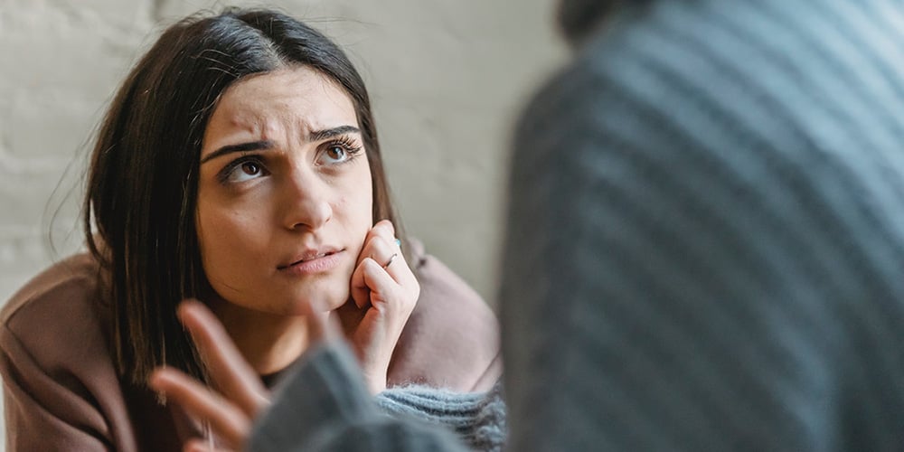 woman looking worried or upset as someone talks to her