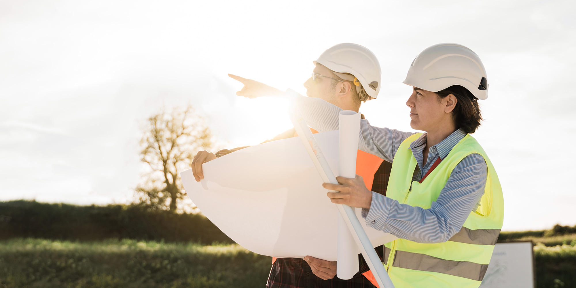 engineers in hard hats surveying with blueprints