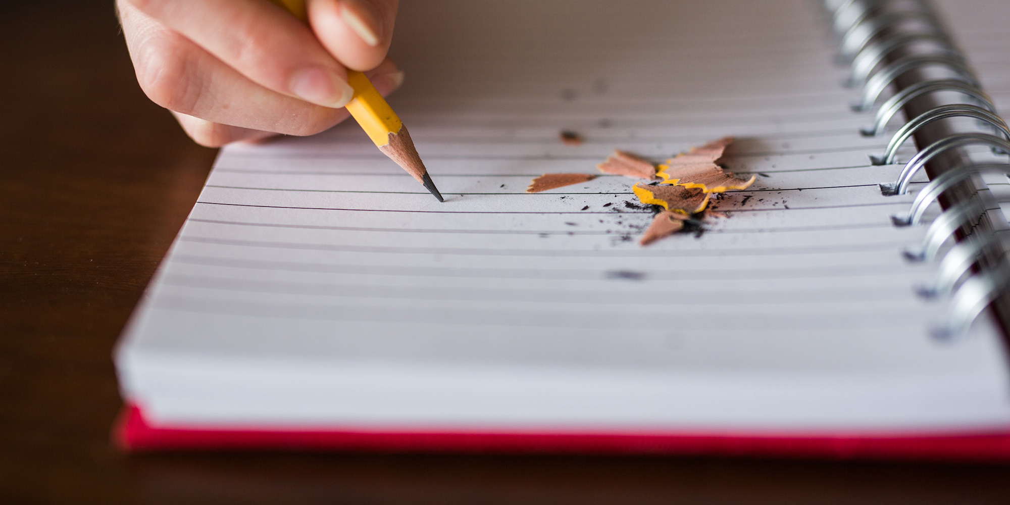 student writing in a notebook with a pencil